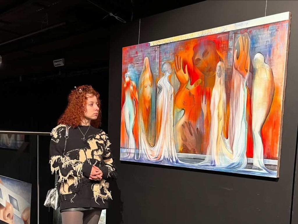 Une artiste à côté de sa peinture grand format