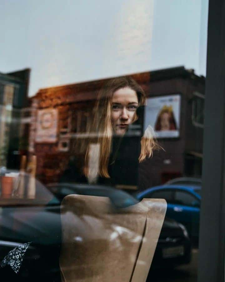 Une artiste reflétée dans une vitrine
