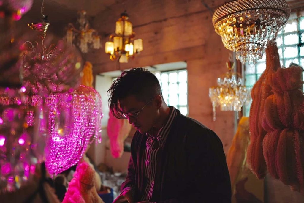 Une artiste dans un intérieur de lustres et de lumière colorée