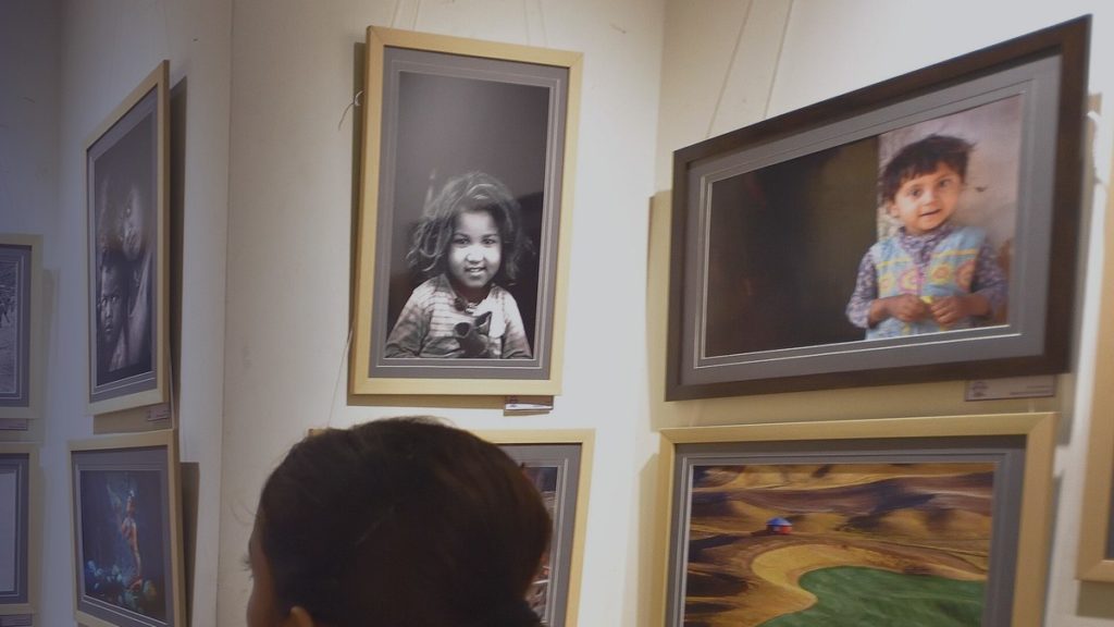 Des visiteurs regardent des photographies encadrées dans une exposition