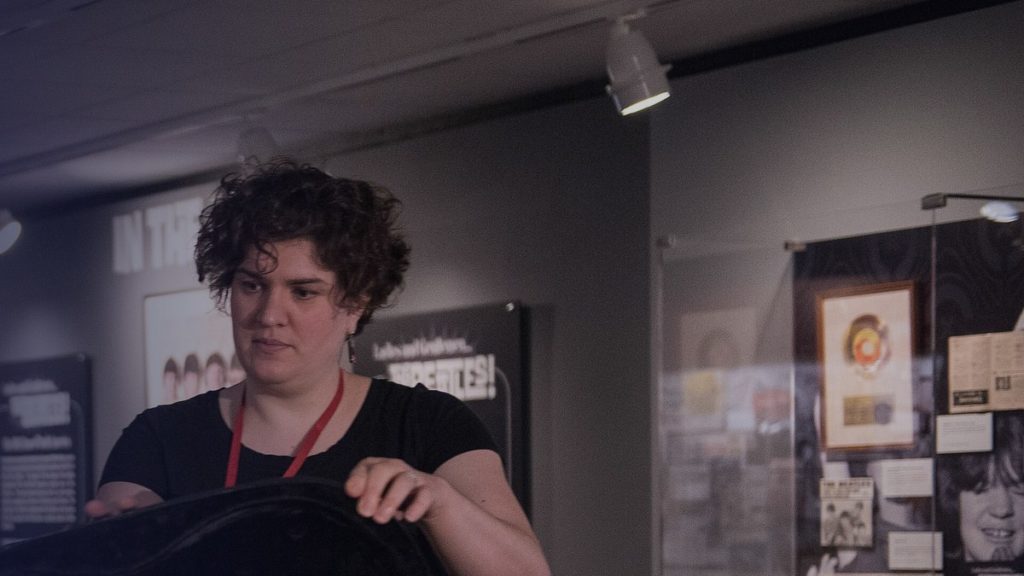 Une femme portant un badge prépare une pièce dans une salle de musée