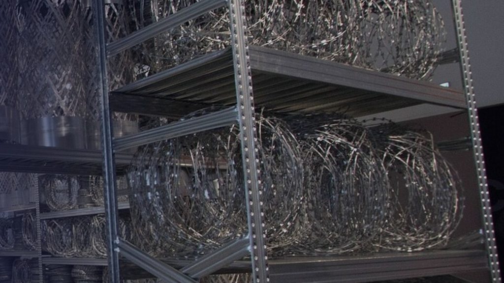 Une installation d’étagères métalliques et de fil de fer enroulé dans un espace d’exposition