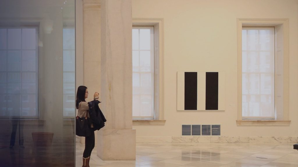 Une visiteuse photographie une œuvre dans une salle de musée lumineuse