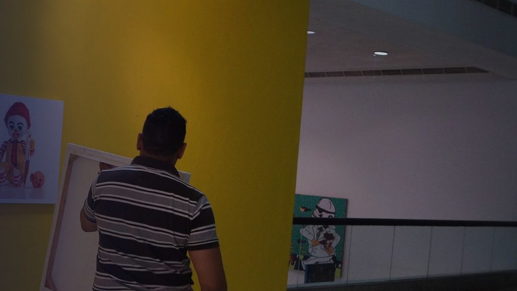 Un artiste accroche des œuvres au mur d’une galerie avant une exposition