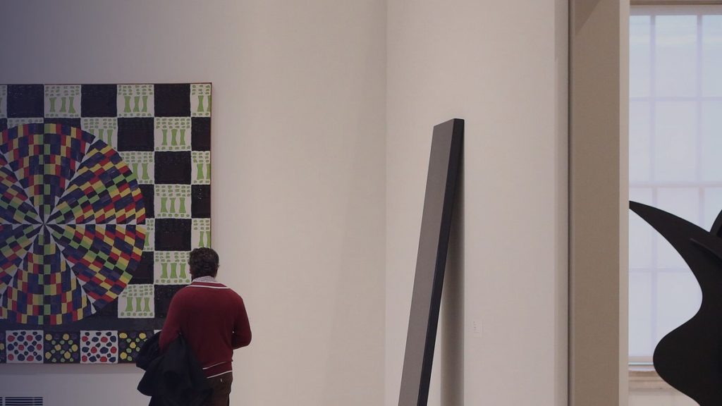 Un visiteur regarde un grand tableau géométrique dans un musée